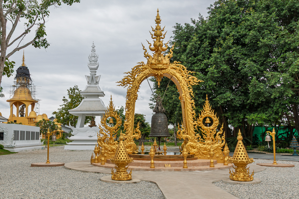 La cloche suspendue La cloche suspendue sous l'arche dorée du temple blanc de Chiang Rai