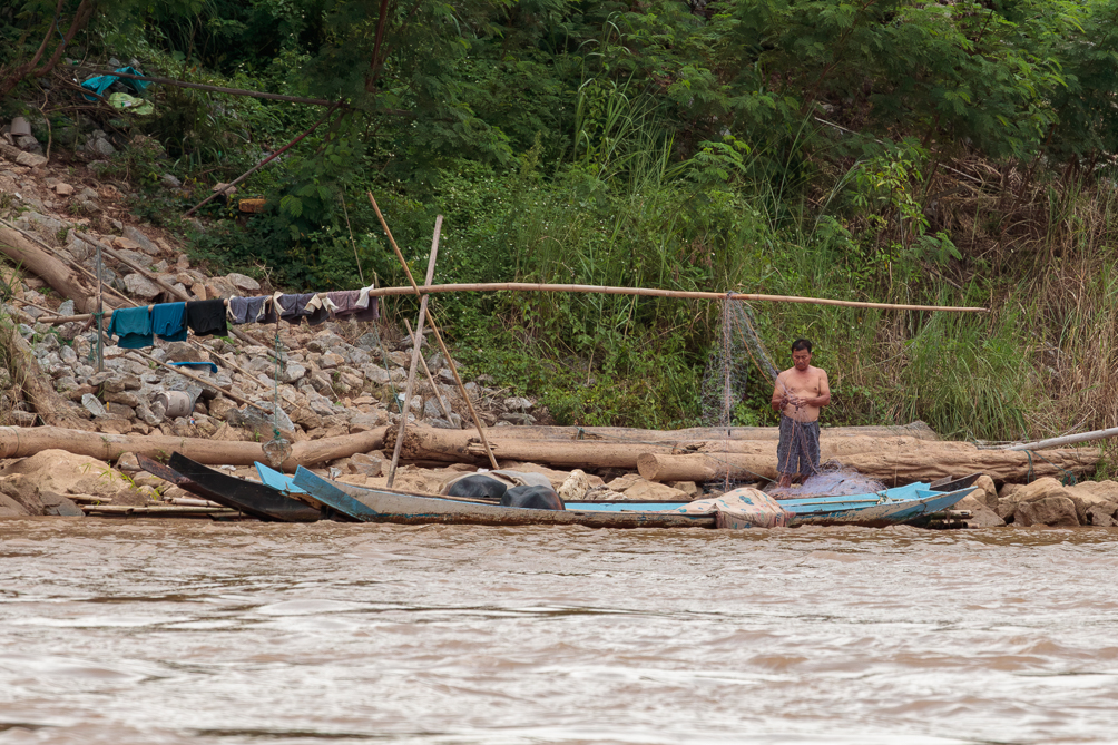 Pêcheur sur le Mékong Pêcheur réparant son filet sur les rive du Mékong